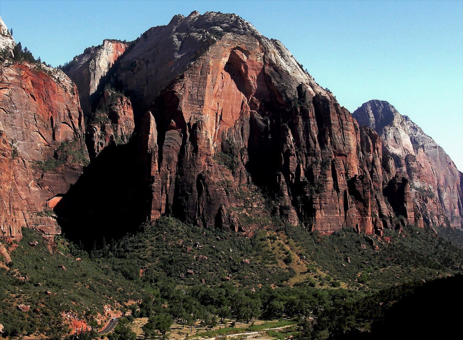 Red Arch Mountain Over Zion Canyon Towering red sandstone cliffs of Red Arch Mountain rise above Zion Canyon's lush green valley floor.