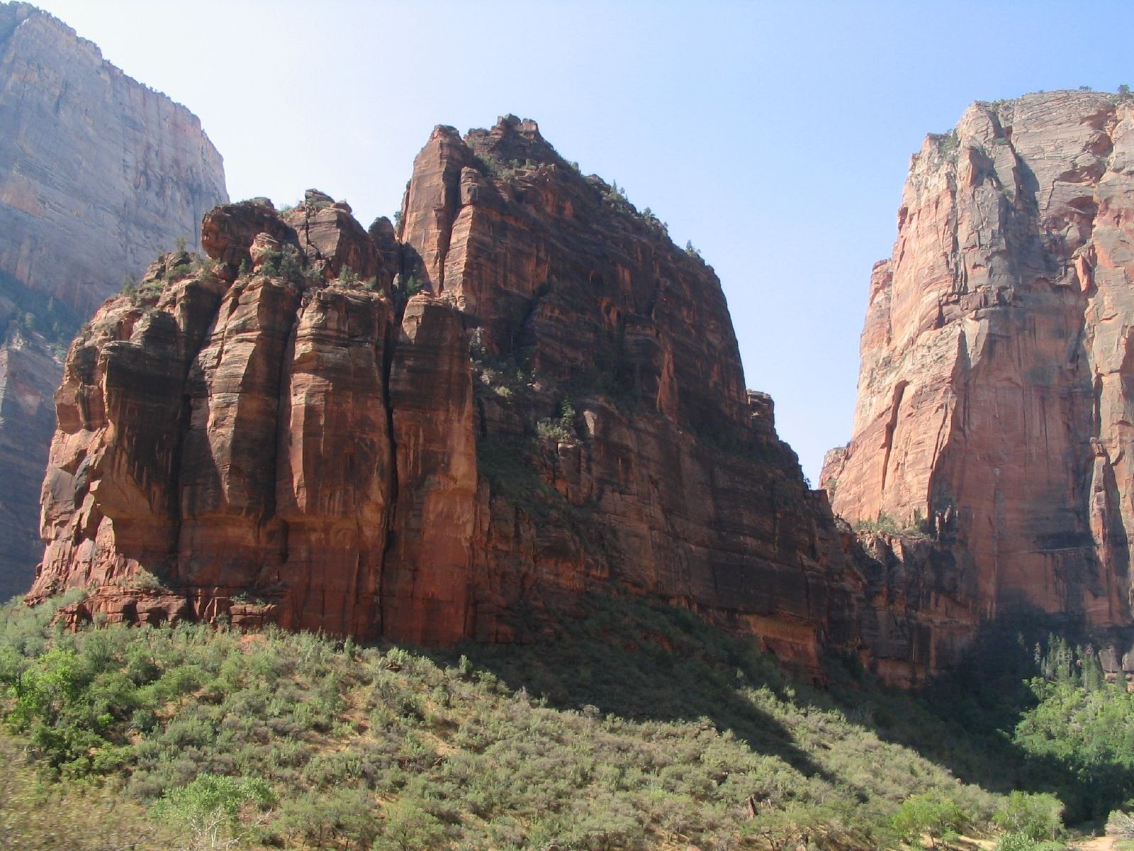 The Organ Monolith in Zion Canyon Massive red sandstone monolith known as The Organ rising above Zion Canyon shrubland beneath a clear blue sky.