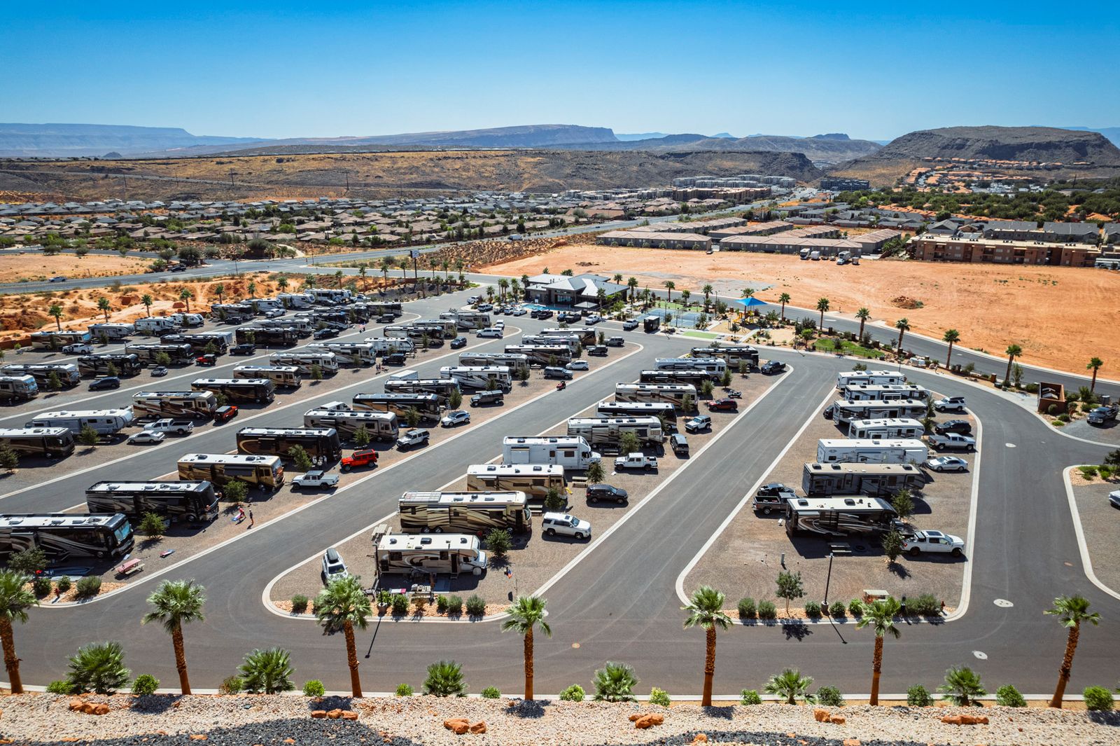 20240917 Drone Shots 169 HDR Aerial view of modern RV park near Zion National Park with palm trees, paved sites, and southern Utah's iconic red rock mesas in background