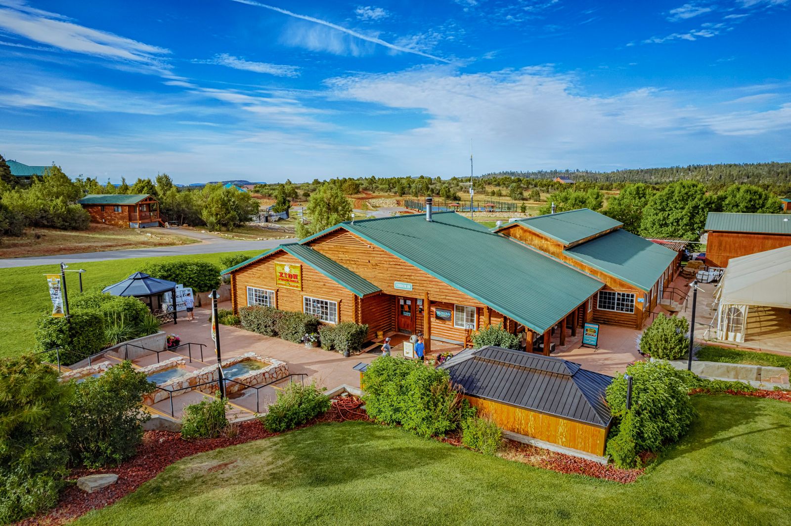 Aerial view of rustic lodge with green metal roof surrounded by cabins and landscaped grounds near Zion National Park