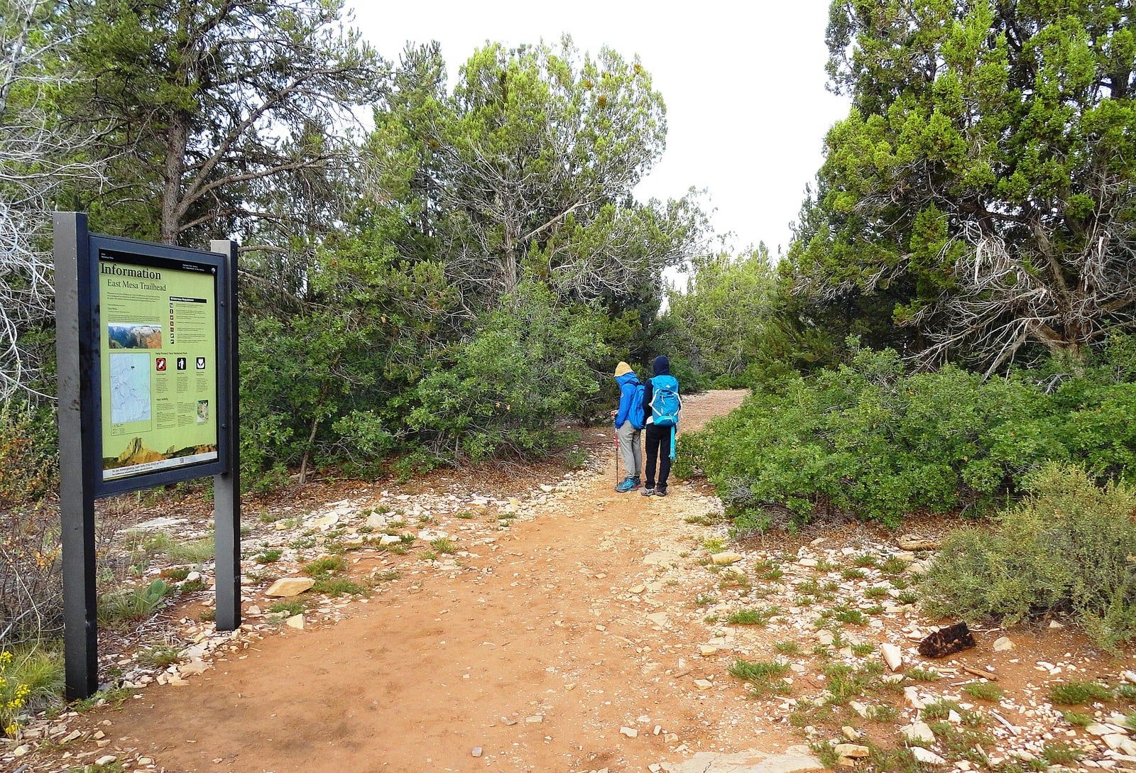 East Mesa Trailhead at Zion National Park Two hikers with backpacks set off from the East Mesa Trailhead information sign in Zion National Park, Utah.
