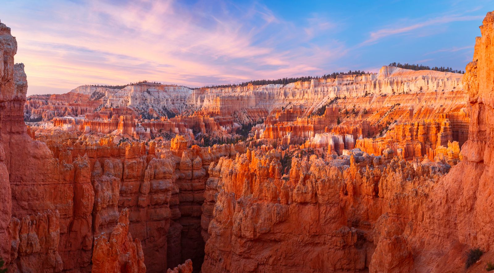 Stunning sunrise view of Bryce Canyon's distinctive red rock hoodoo formations and towering stone spires under golden morning light in southern Utah.