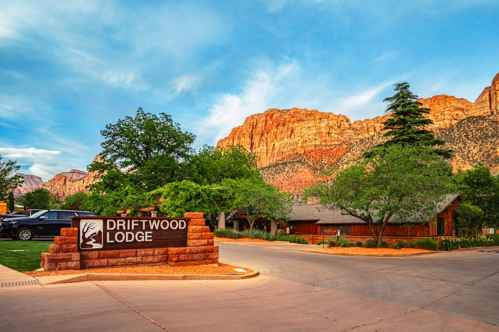 Driftwood Lodge entrance sign with stunning red rock canyon cliffs backdrop in Springdale offering hotels near Zion National Park Utah lodging accommodations