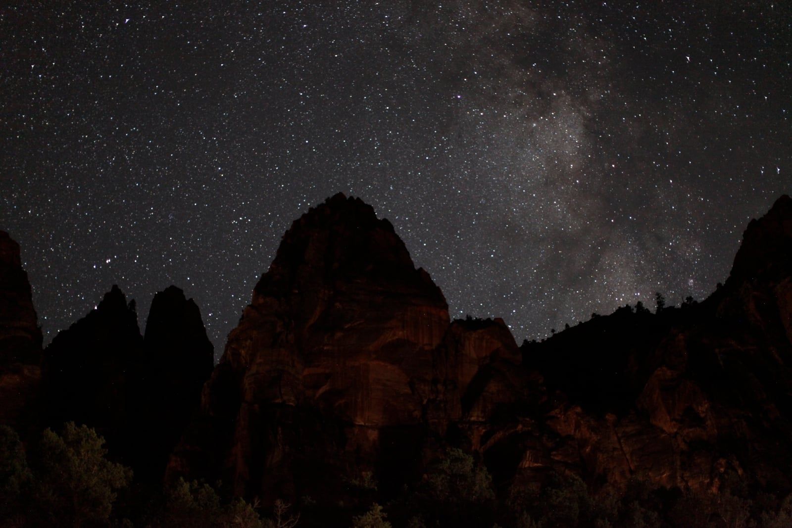Milky Way Over Zion Canyon at Night The Milky Way stretches over dramatic red rock canyon silhouettes in Zion National Park, Utah at night.