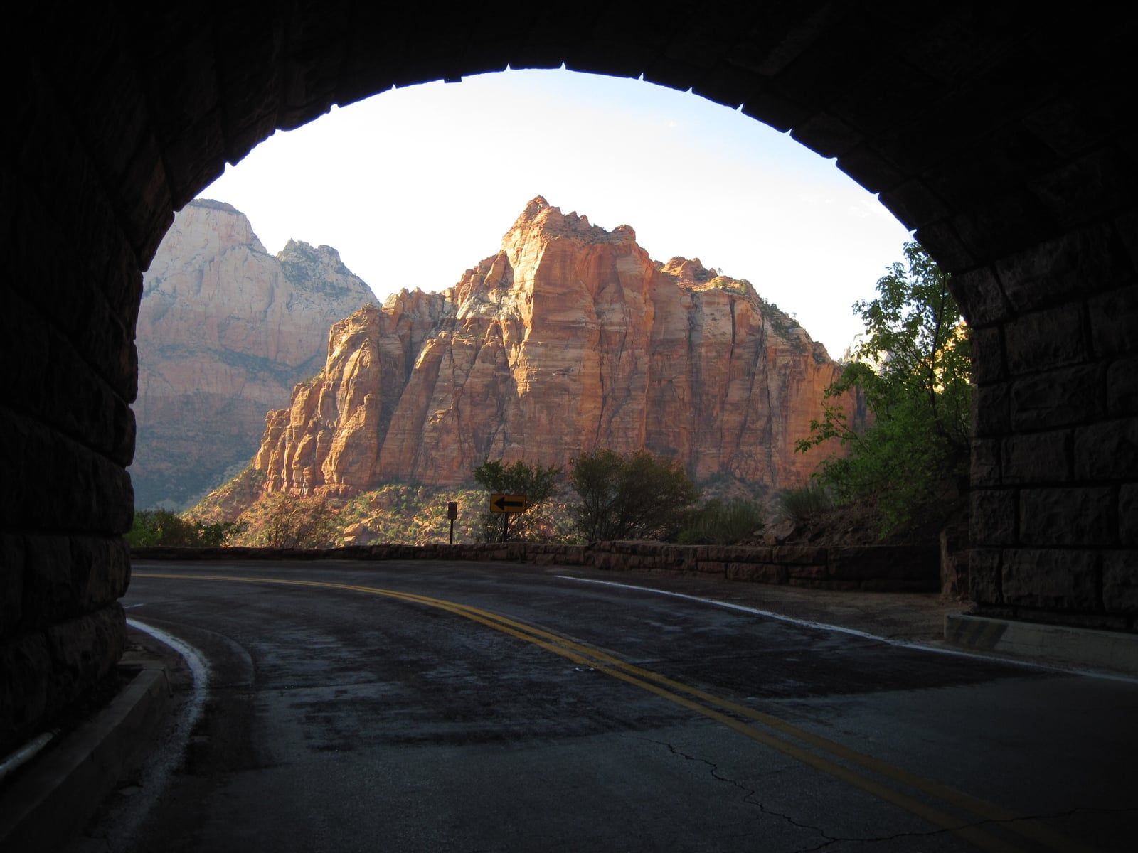 View of Zion's red rock cliffs framed by a tunnel entrance with a clear blue sky.