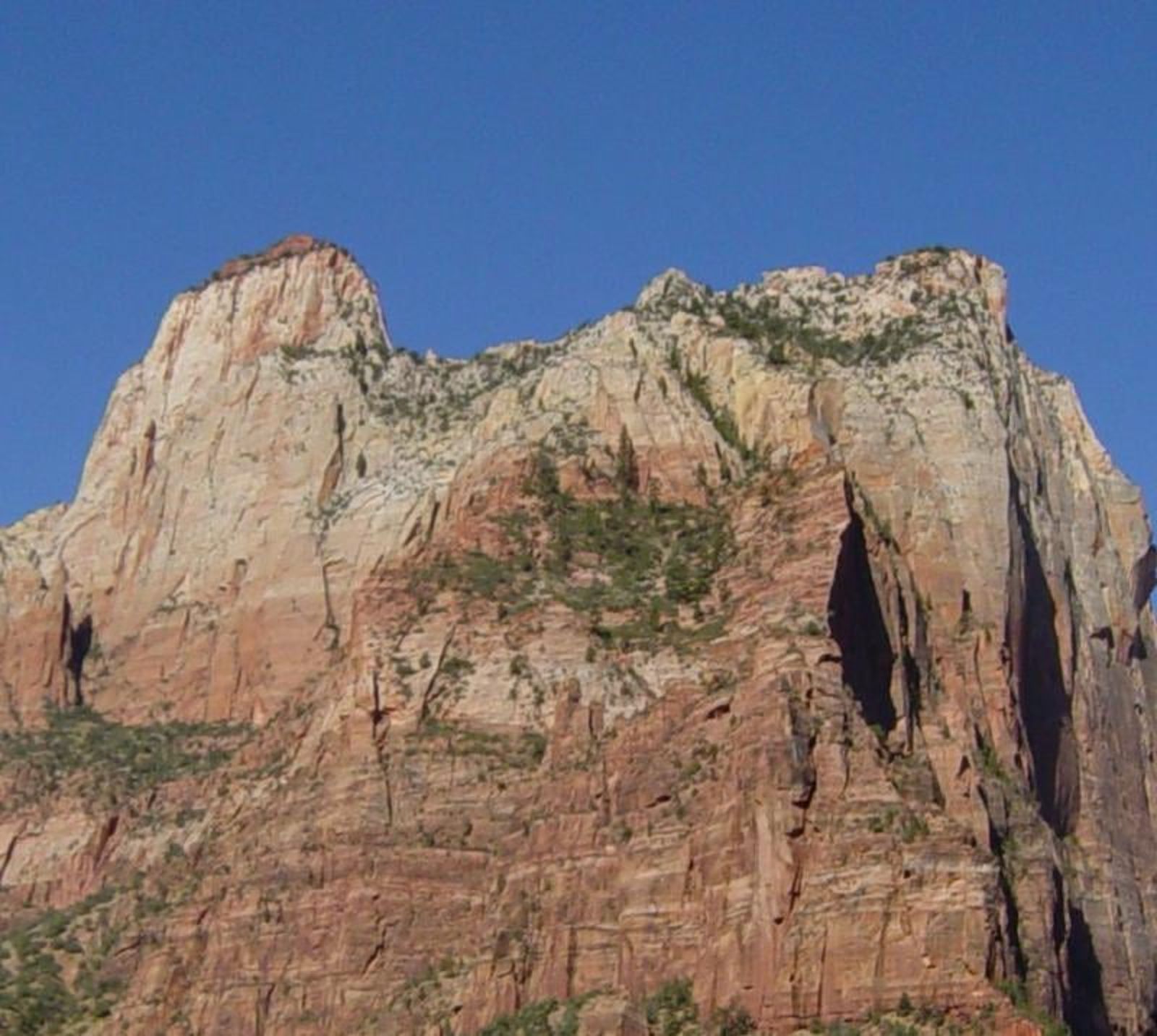 The Sentinel Peak in Zion Canyon The Sentinel's towering sandstone cliffs rise dramatically above Zion Canyon under a clear blue sky.
