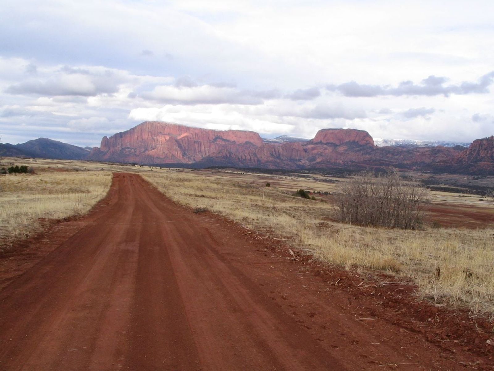 Red Dirt Road Toward Kolob Canyon, Zion A red dirt road stretches toward dramatic red rock mesas near Kolob Canyon in Zion National Park, Utah.