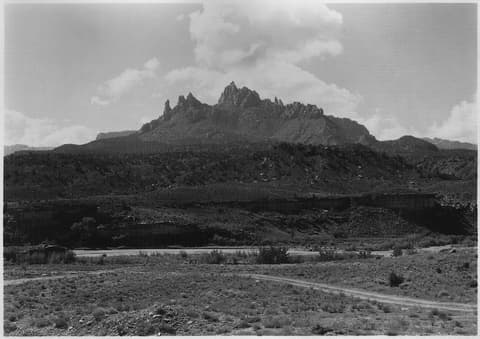 Historic black and white view of Eagle Crag's jagged rocky spires rising above the desert floor south of Zion Canyon.