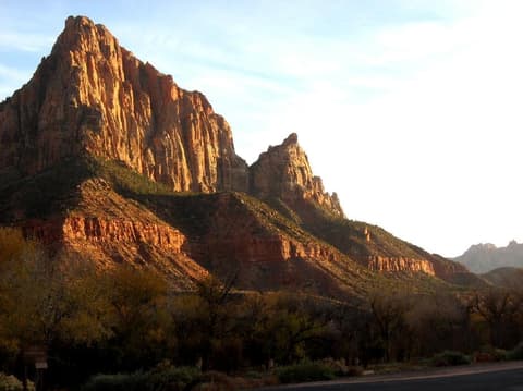 The Watchman peak glows in warm golden light above Zion Canyon near the park entrance in southern Utah.