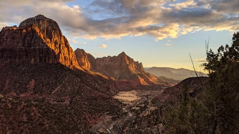 Golden sunset light bathes the Watchman and sandstone cliffs above Zion Canyon in southern Utah.