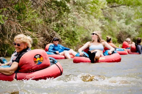 Group of people tubing down the Virgin River in Zion National Park, southern Utah, enjoying an outdoor adventure and water activities in the scenic natural landscape.