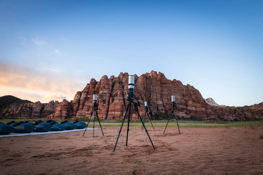 A scenic overlook in Zion National Park with red rock formations and telescopes set up for stargazing at sunset.